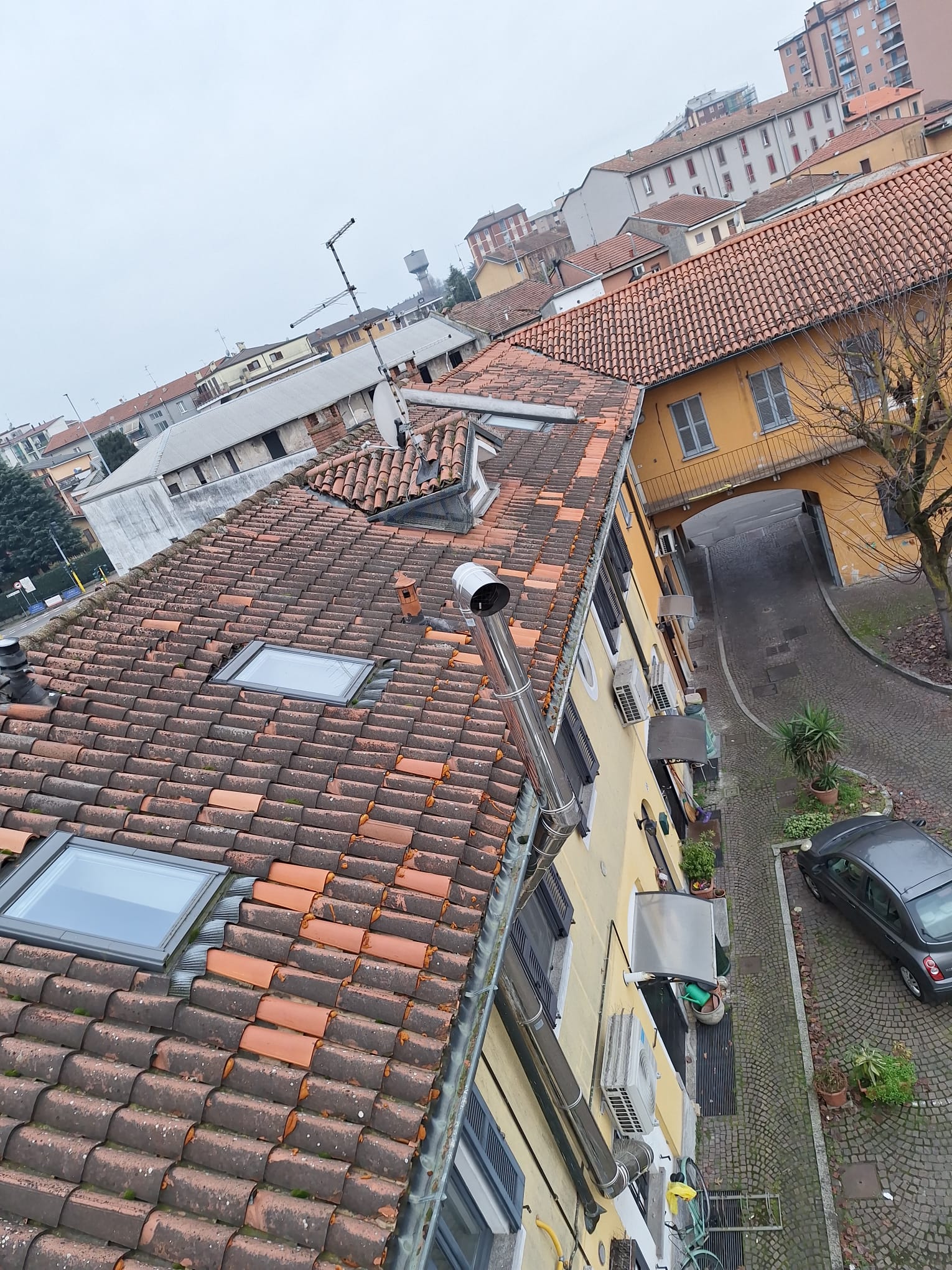 A high-angle view looks across tiled rooftops, skylights, and surrounding buildings.